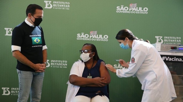 A enfermeira M�nica Calazans recebeu a primeira dose da vacina, aplicada pela tamb�m enfermeira J�ssica Pires de Camargo, observadas pelo governador Jo�o D�ria (Imagem: GovSP).